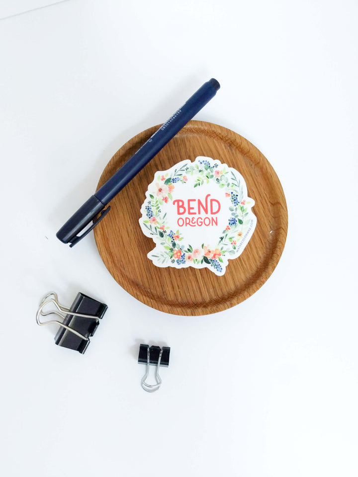 a desk with a pen, paper clips, and a pen holder with a stack of bend, or stickers