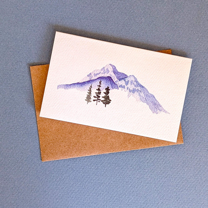 a card with a watercolor painting of a mountain