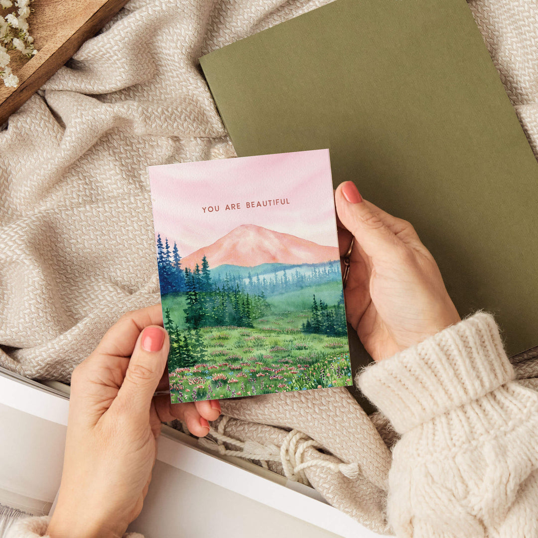 a person holding a card with a mountain scene on it