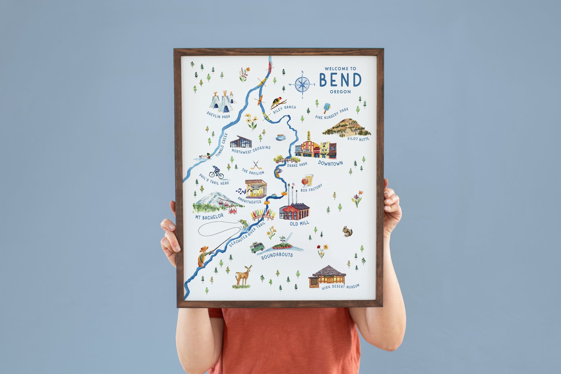 a person holding up a framed map of bend