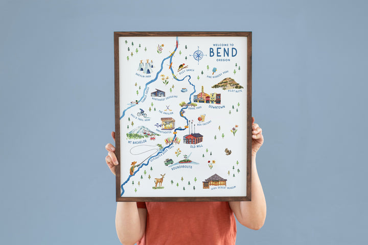 a person holding up a framed map of bend