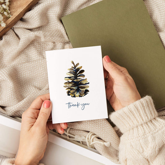 a person holding a card with a pine cone on it