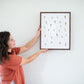 a woman holding up a framed picture of birds