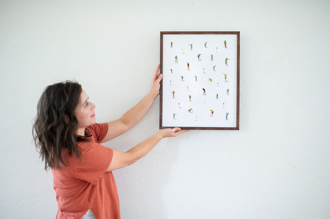 a woman holding up a framed picture of birds