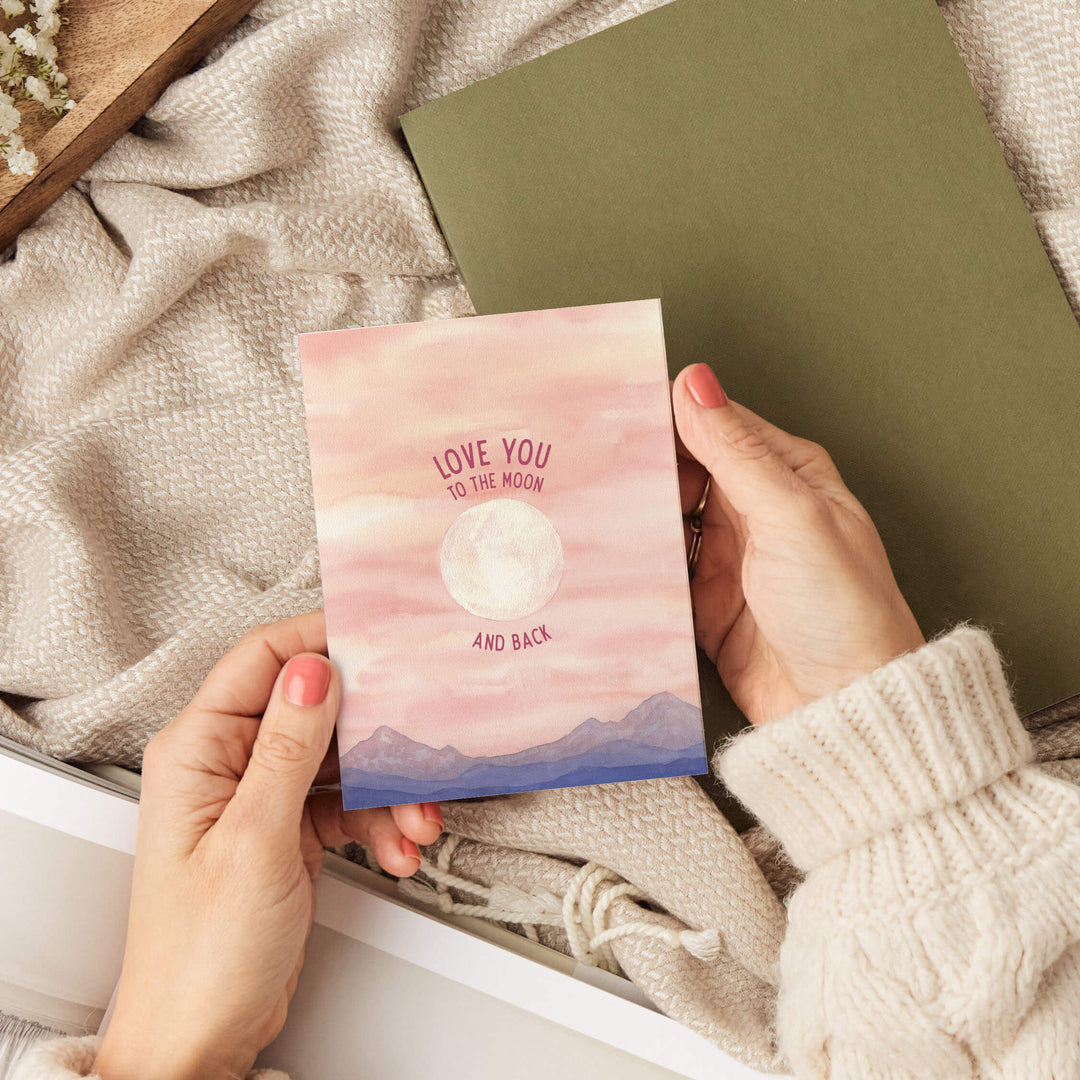 a person holding a card with the words love you to the moon and back