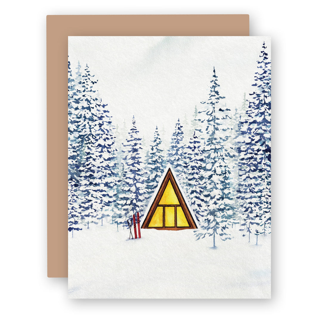 a card with an aframe cabin in the middle of a snowy forest