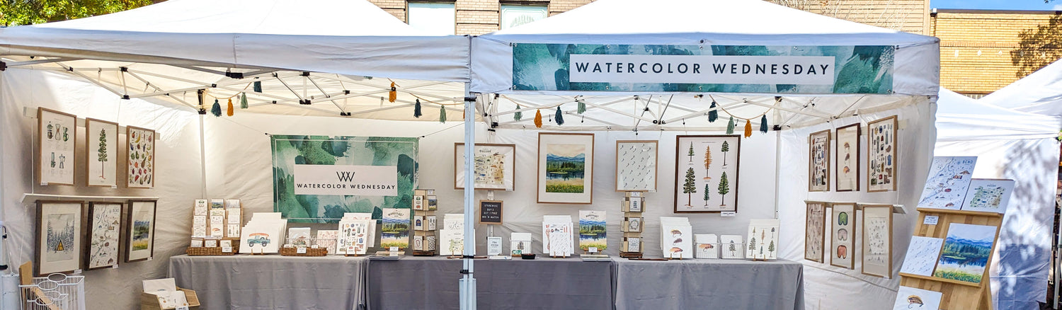 Watercolor Wednesday vendor booth set up at an arts festival in Bend, Oregon