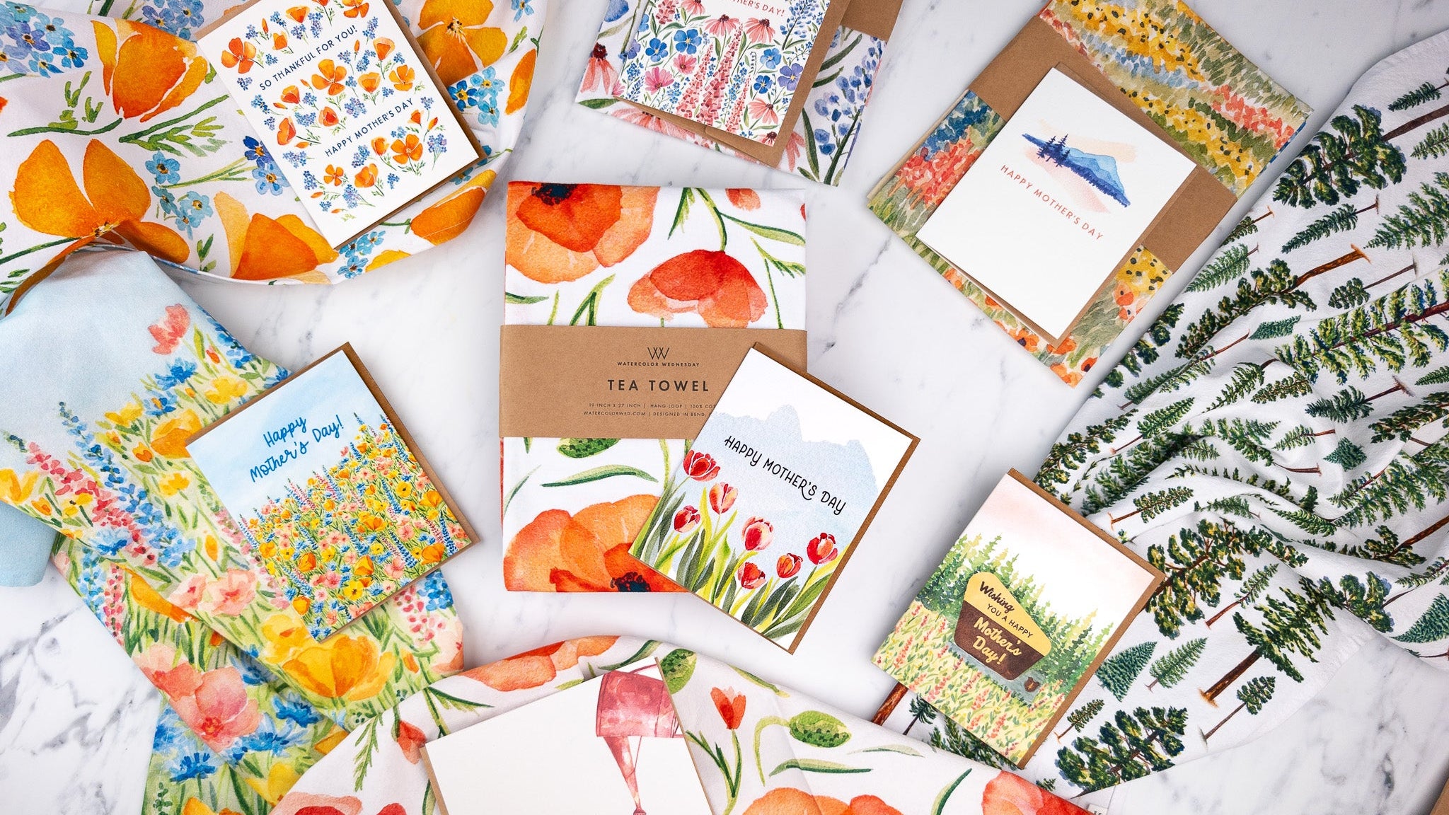 Collection of colorful mother's day greeting cards and tea towels on a marble surface