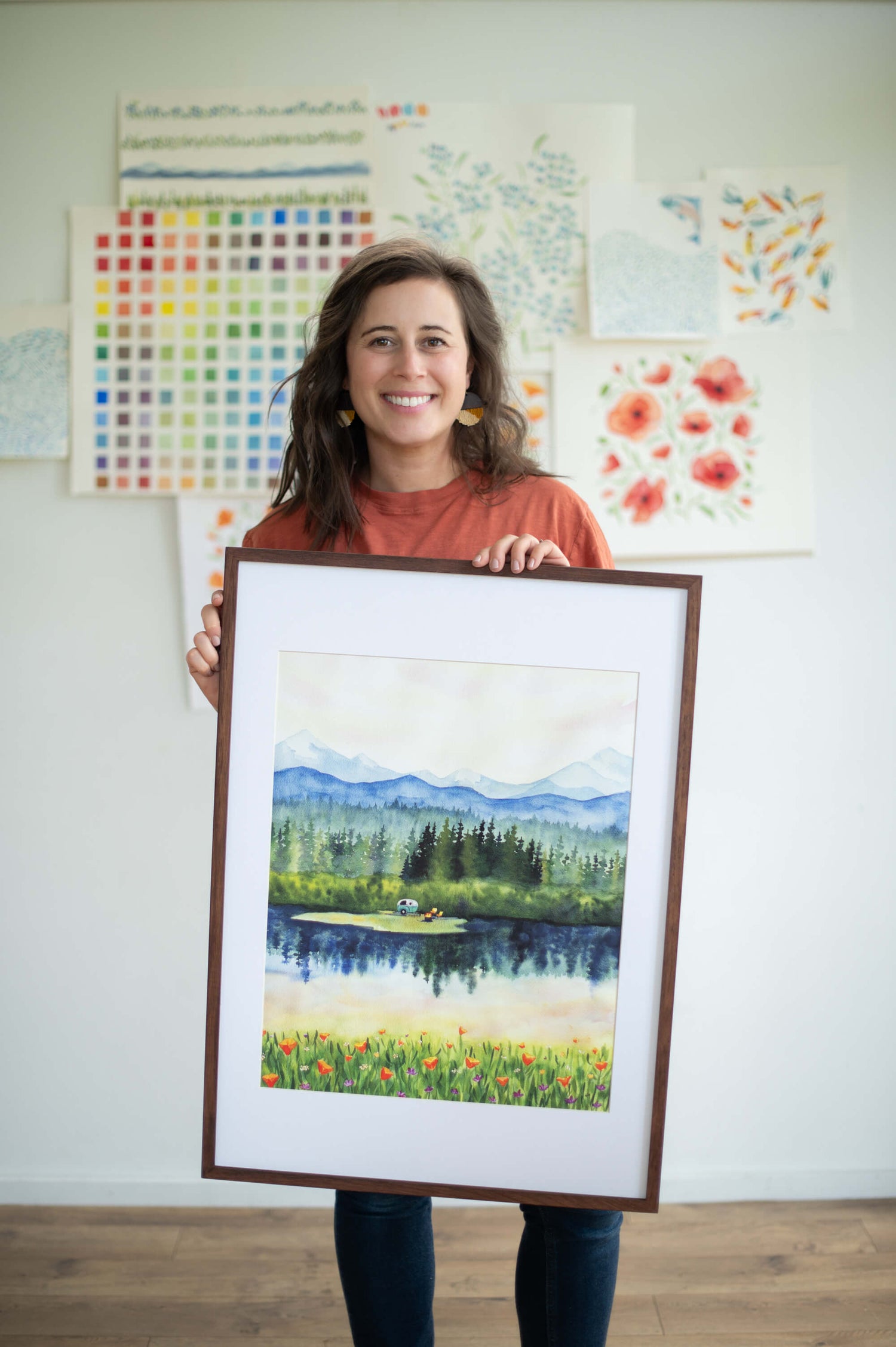 Bend, OR Watercolor Artist Kirsten holding a large adventure art prints