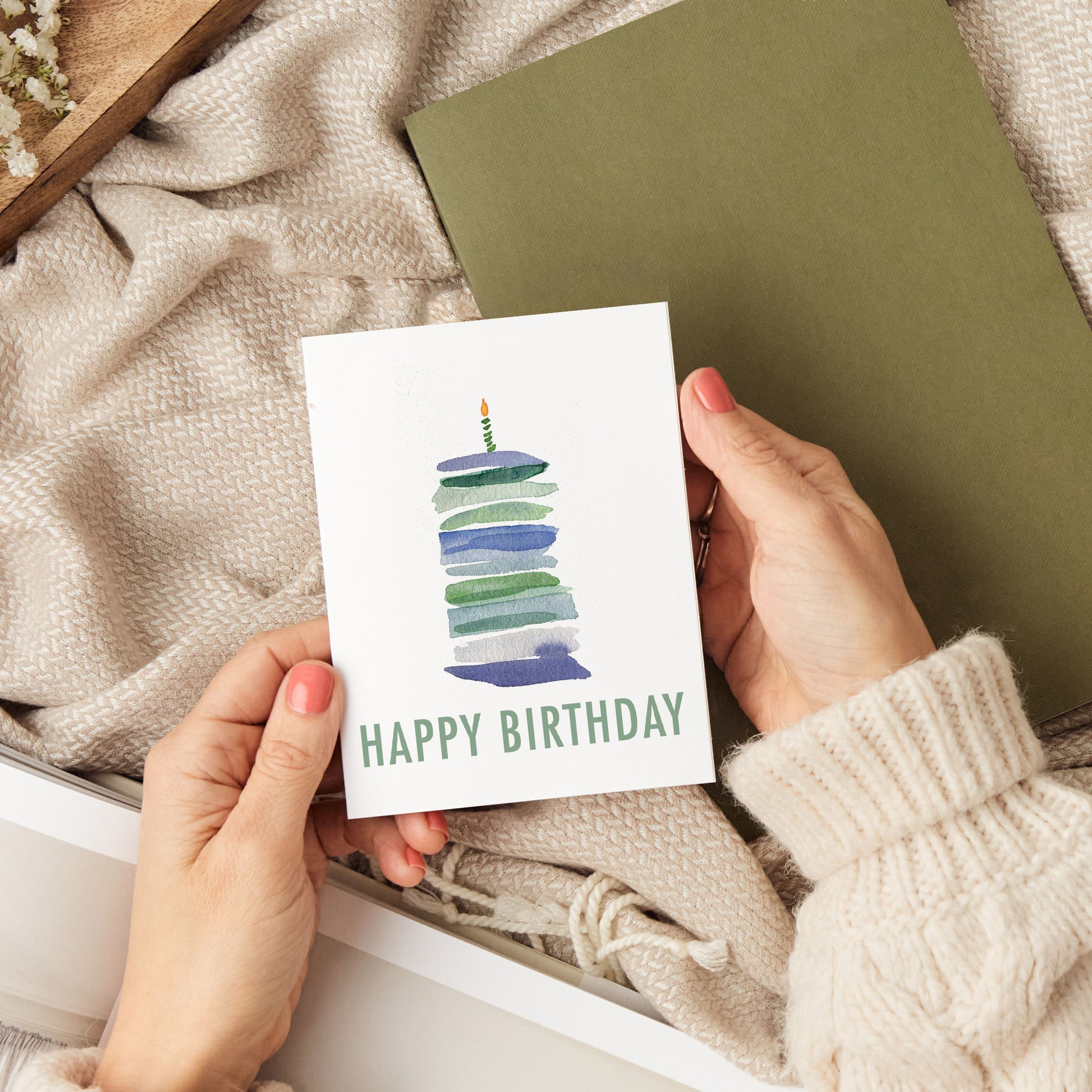 a person holding a birthday card with a cake on it