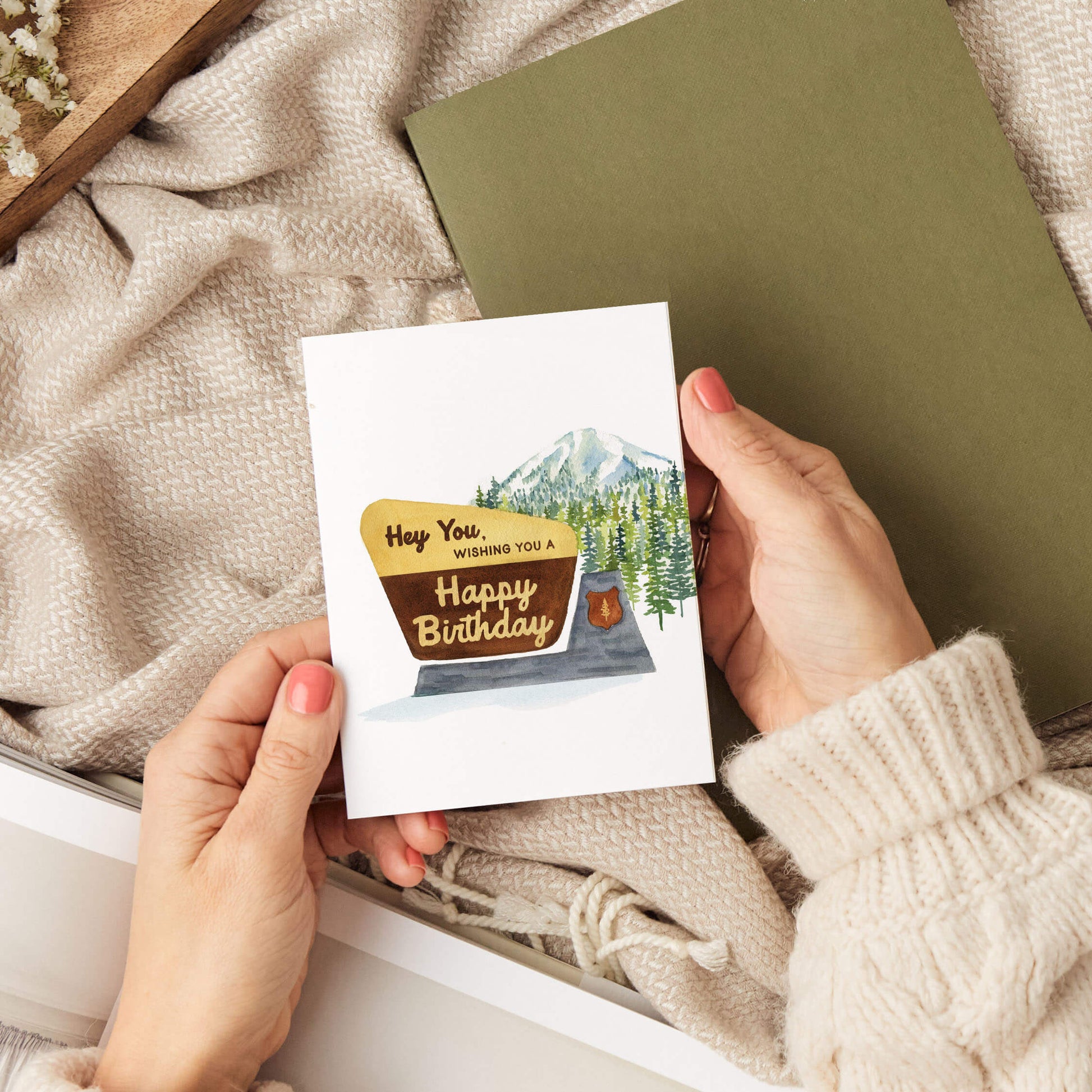 a person holding a card with a mt. rainier mountain scene on it