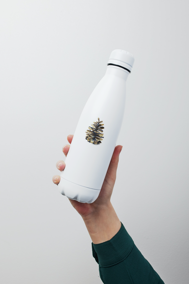 a person holding a white water bottle in their hand with a pinecone sticker on it