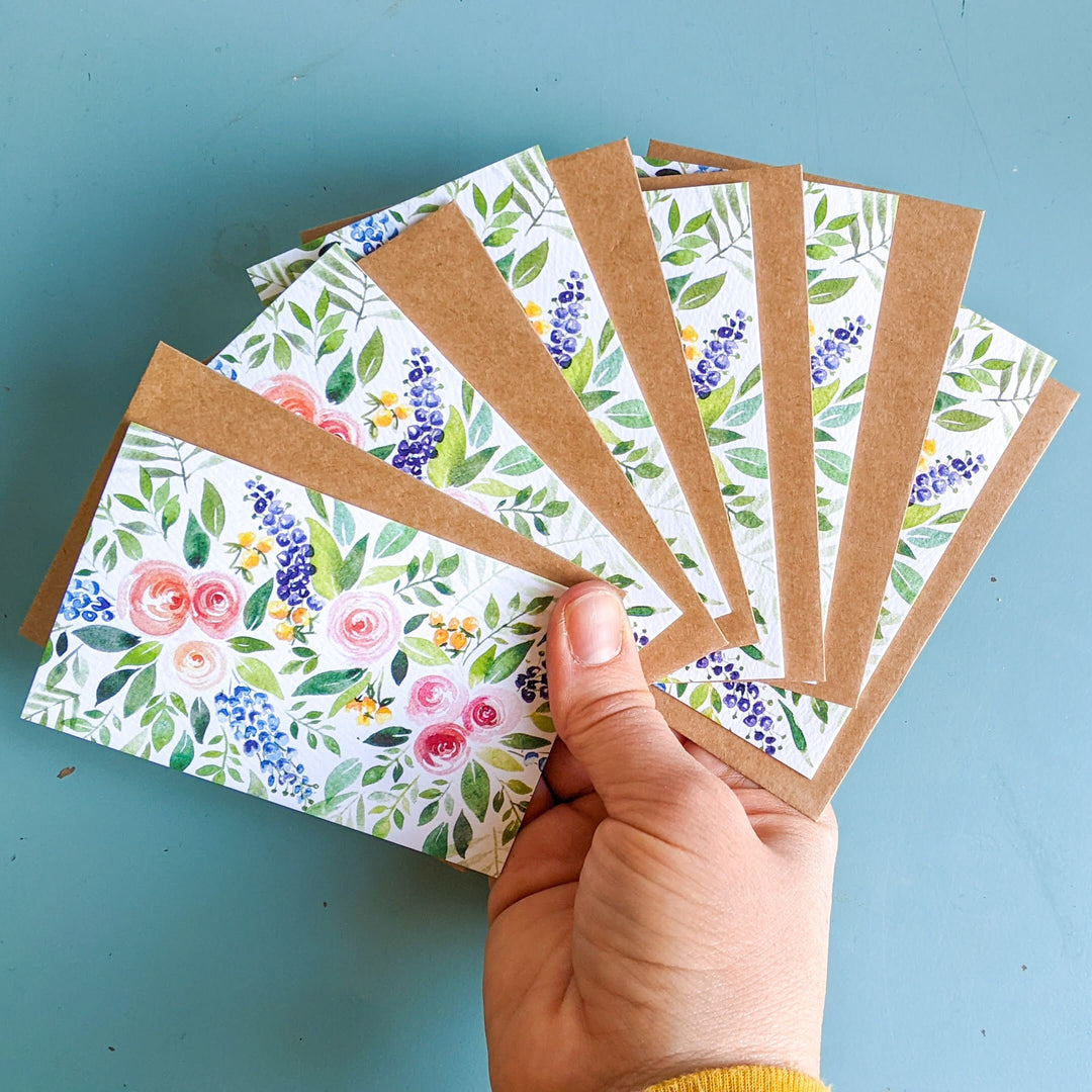 a person holding a bunch of cards with flowers on them